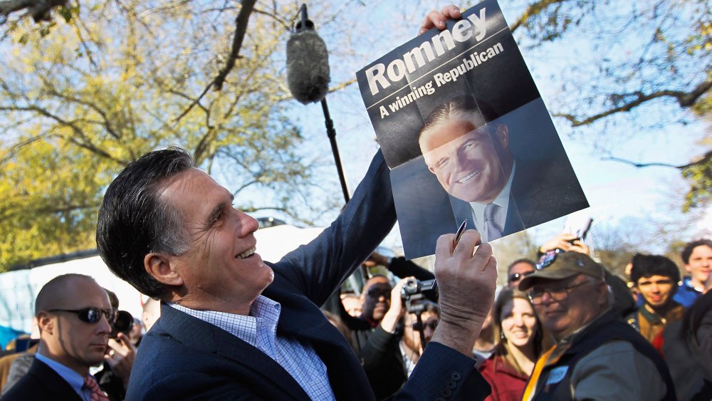 Mitt Romney tenant une affiche de son père, George Romney