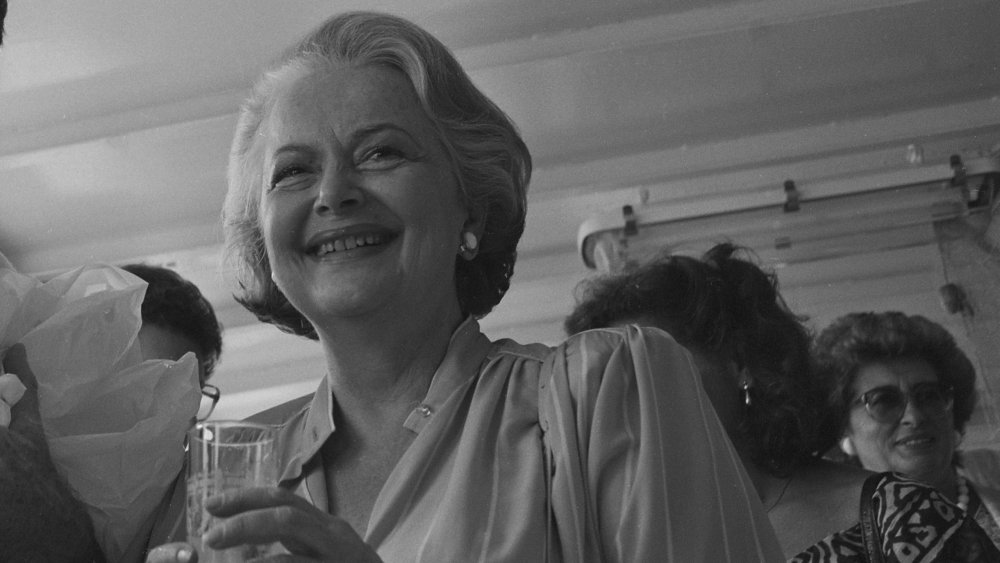 Photo en noir et blanc d'Olivia de Havilland souriant et tenant un verre