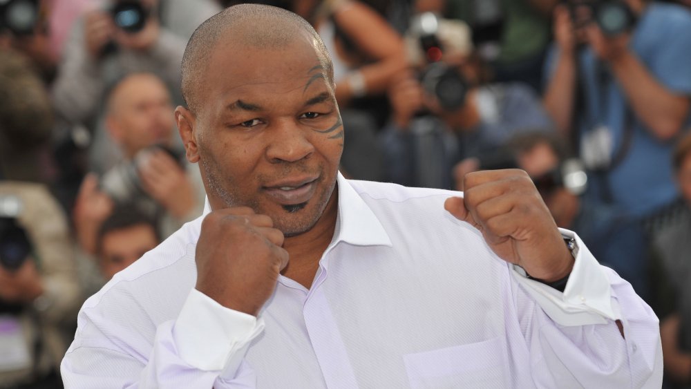 Mike Tyson avec les poings levés, posant en chemise blanche