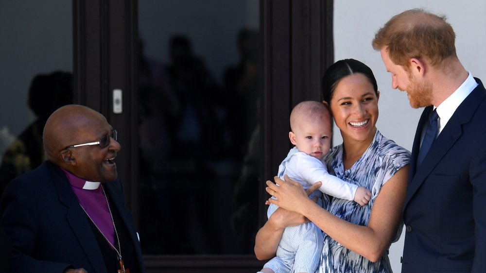 Desmond Tutu regardant bébé Archie dans les bras de Meghan Markle à côté du prince Harry