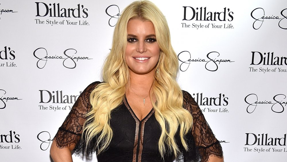 Jessica Simpson dans un haut de dentelle noire, souriant avec ses mains sur ses hanches