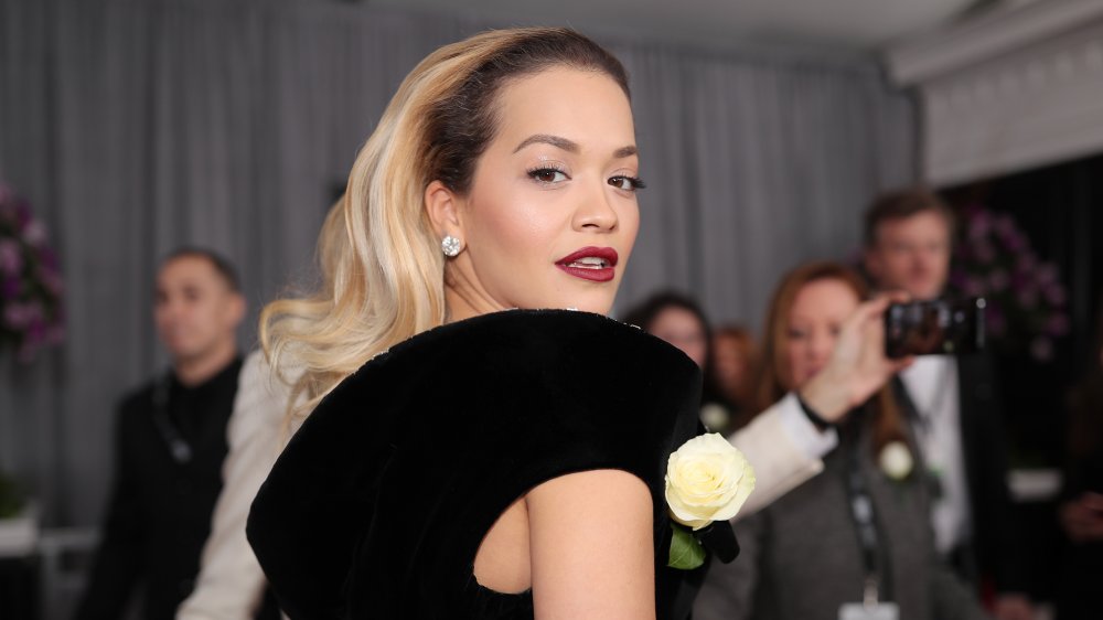 Rita Ora dans une robe noire, regardant par-dessus son épaule