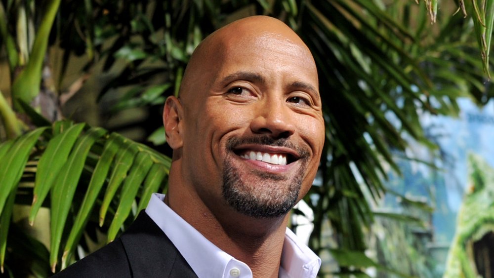 Dwayne 'The Rock' Johnson souriant devant un palmier