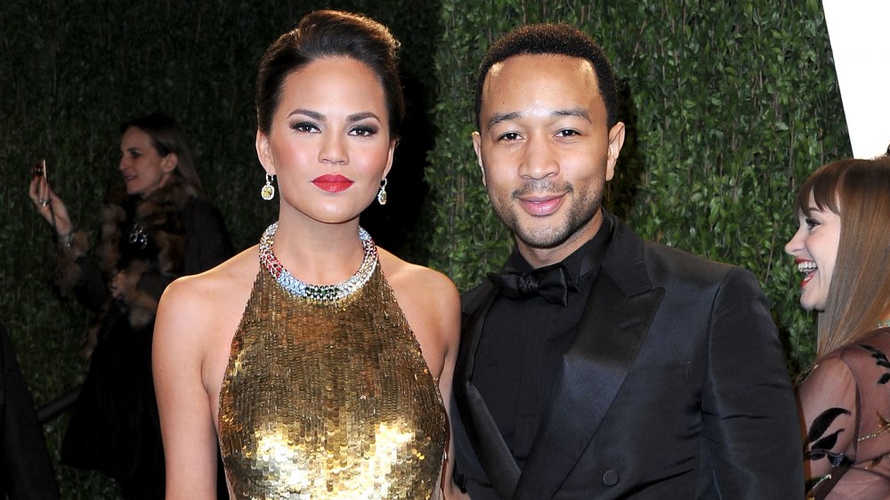 Chrissy Teigen dans une robe d’or debout avec John Legend