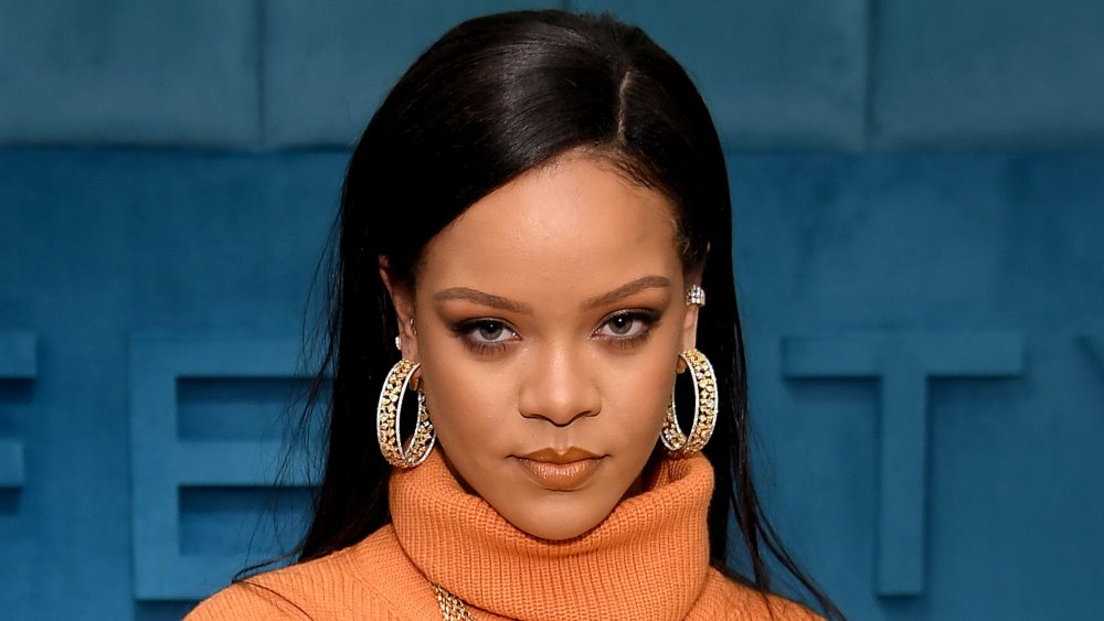 Rihanna dans une robe orange de cou de tortue, posant avec une expression sérieuse