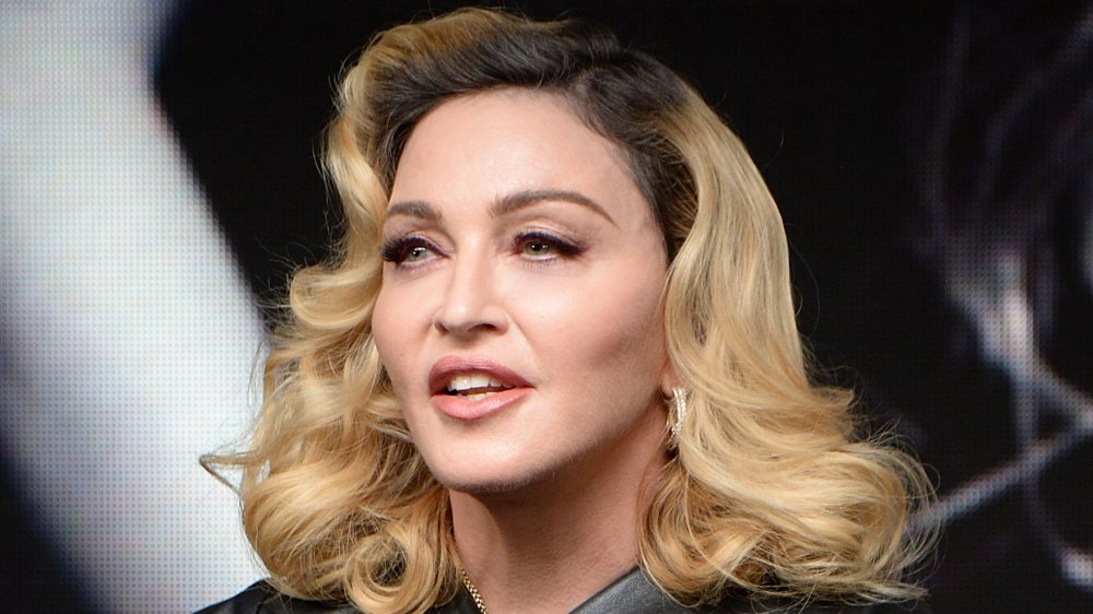 Madonna dans une tenue en cuir noir, parlant tout en regardant outre du côté