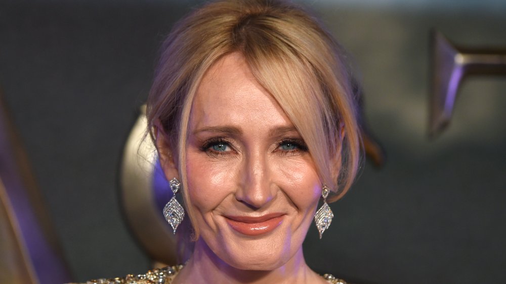 J.K. Rowling dans une robe scintillante d’or, souriant avec ses cheveux vers le haut