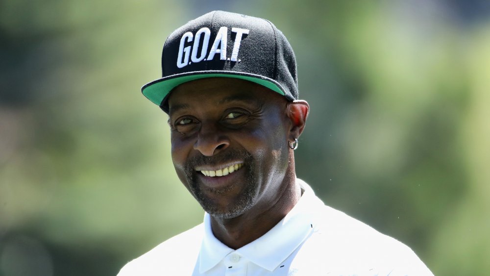 Jerry Rice souriant dans un polo blanc et un chapeau noir de CHÈVRE