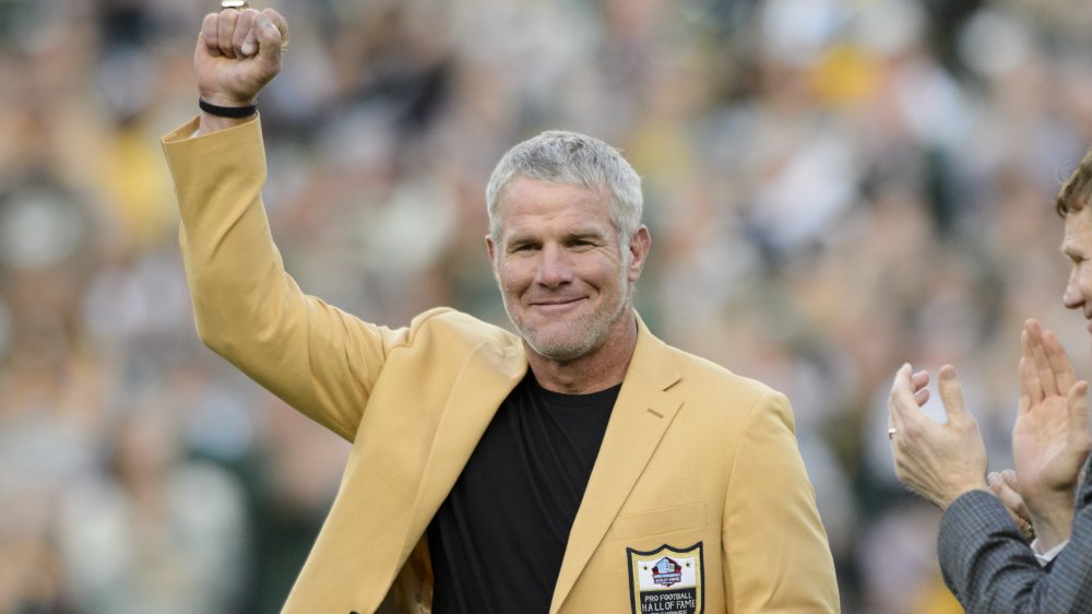 Brett Favre dans un blazer jaune de Hall of Fame, posant avec son poing vers l’air à un jeu