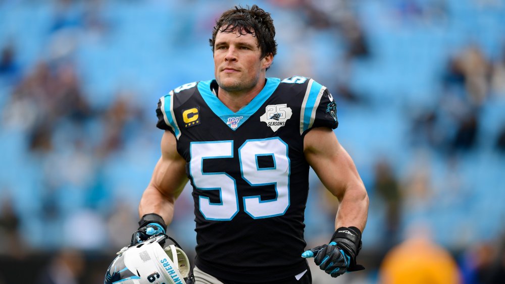 Luke Kuechly courant sur le terrain, tenant son casque