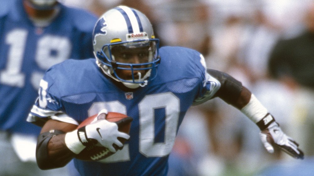 Barry Sanders en cours d’exécution sur le terrain, serrant un ballon de football