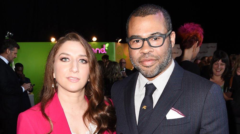 Chelsea Peretti dans un blazer rose, Jordan Peele dans un costume noir et bleu à rayures et des lunettes