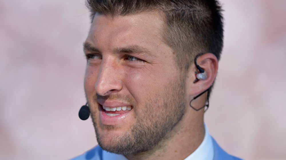 Tim Tebow parlant dans un micro, regardant sur le côté