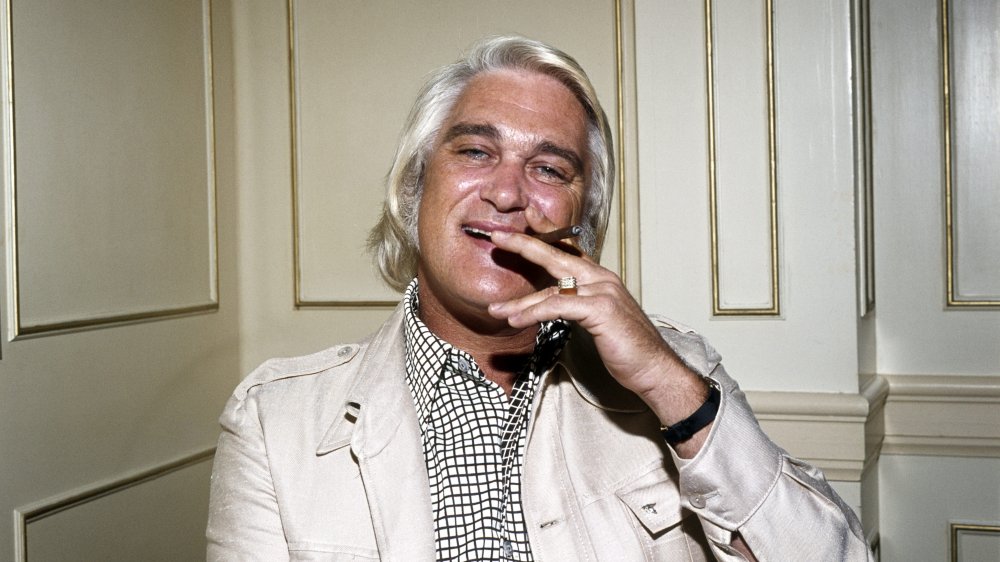 Charlie Rich assis en arrière, souriant, et fumant