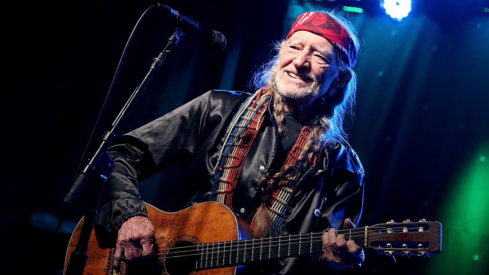 Willie Nelson souriant tout en jouant de la guitare