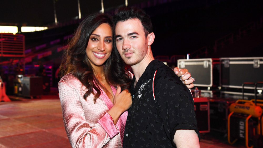 Danielle Deleasa dans un blazer rose, étreignant Kevin Jonas