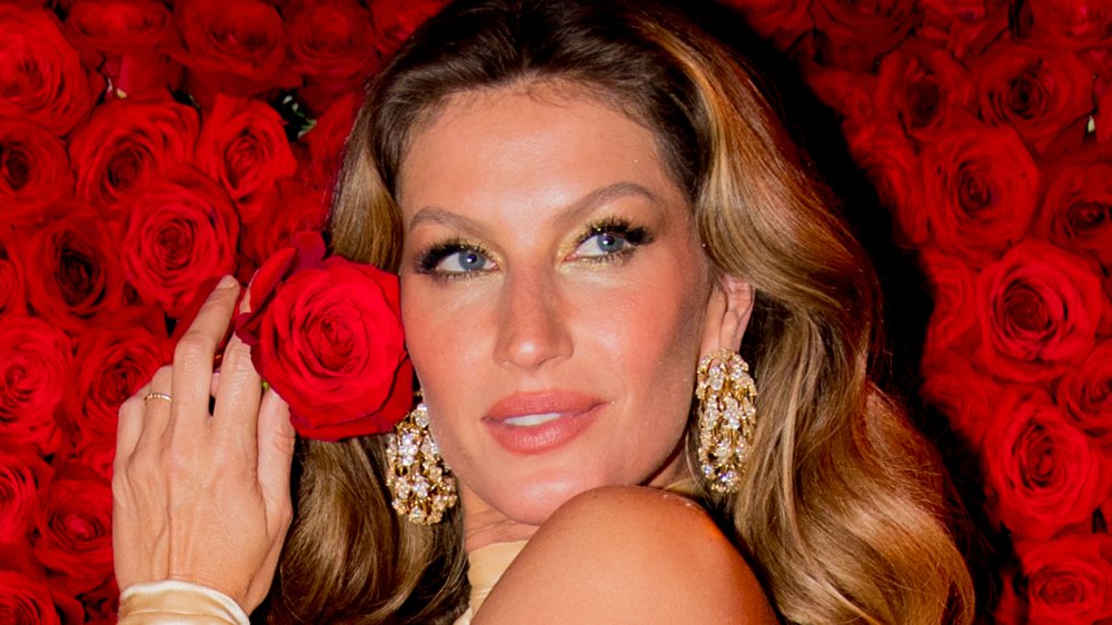 Gisele Bündchen tenant une rose devant un mur de rose