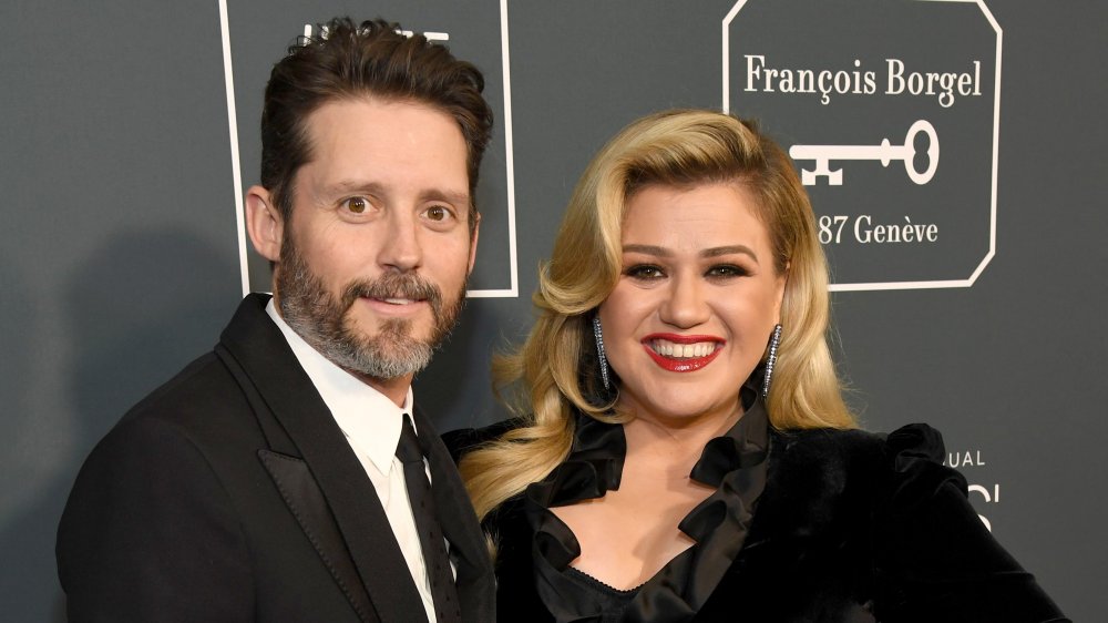 Brandon Blackstock et Kelly Clarkson, tous deux souriants tout en posant bras dessus bras dessous sur le tapis rouge