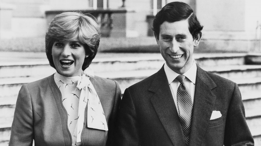 Photo en noir et blanc de la princesse Diana et du prince Charles bras dessus bras dessous et souriant