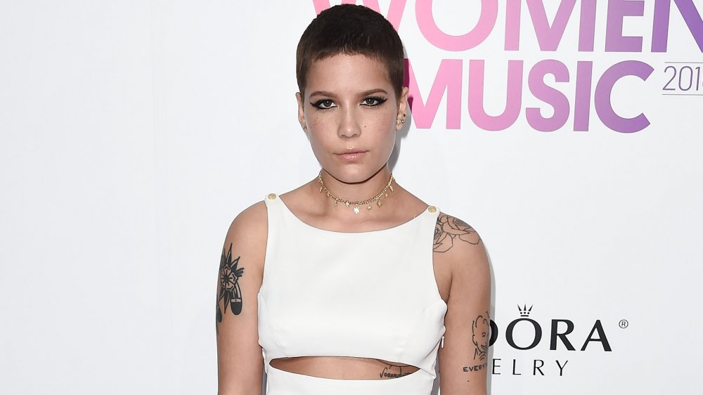 Halsey avec les cheveux courts foncés et les tatouages sur des bras