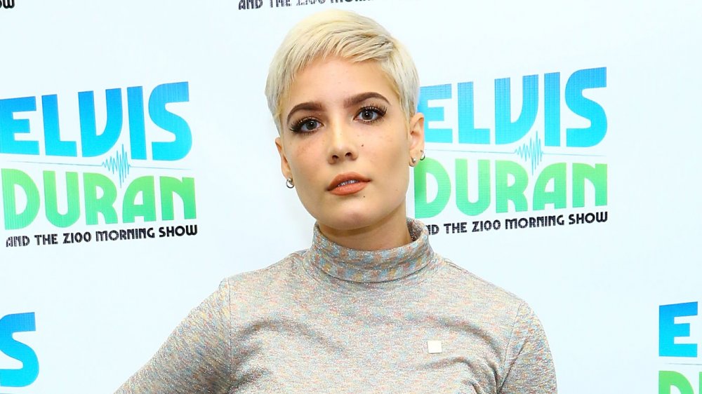 Halsey avec les cheveux blonds courts et le dessus gris de sick-cou