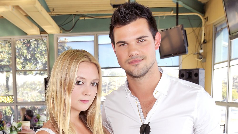 Billie Lourd et Taylor Lautner, tous deux en tenue blanche et posant bras dessus bras dessous