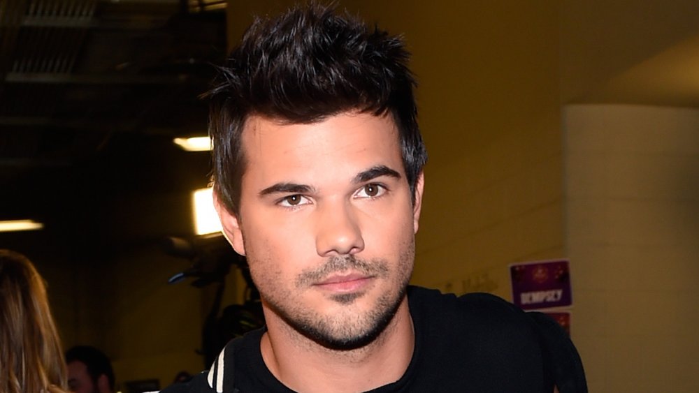 Taylor Lautner portant du noir, marchant tout en regardant sur le côté