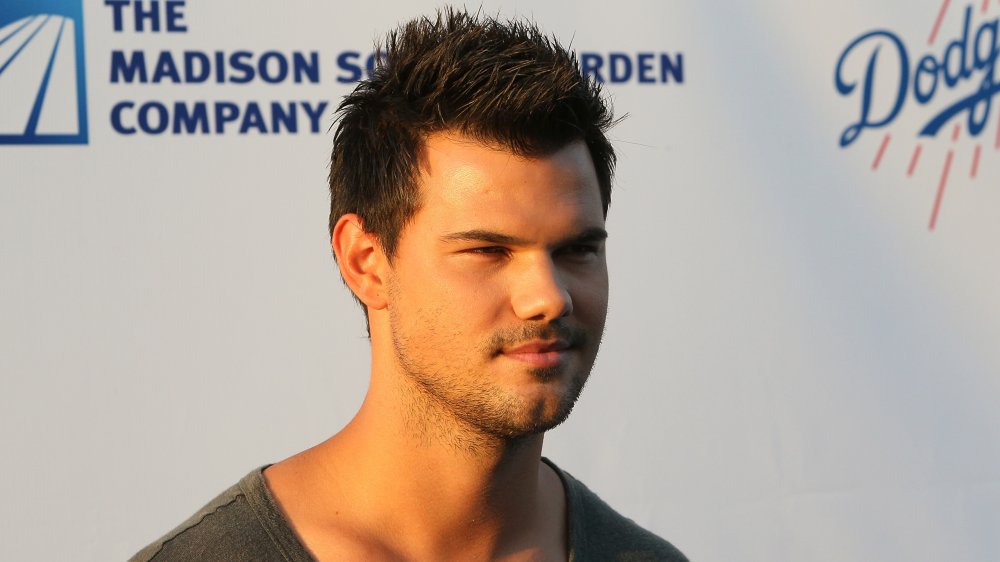 Taylor Lautner dans un t-shirt gris, posant avec une expression sérieuse et regardant sur le côté