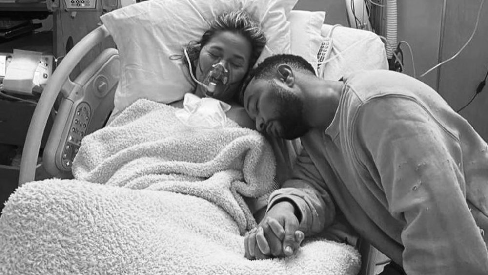 Chrissy Teigen et John Legend se tenant la main et se reposant dans sa chambre d'hôpital