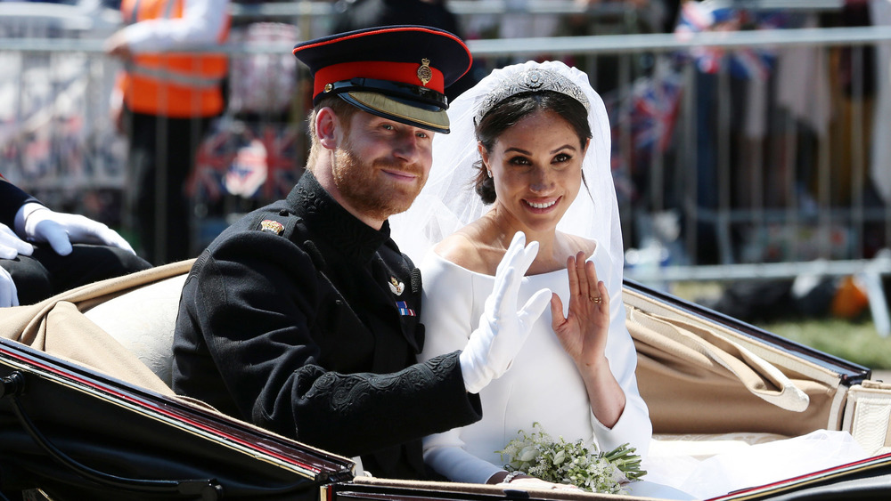 Le prince Harry et Meghan Markle agitent une voiture