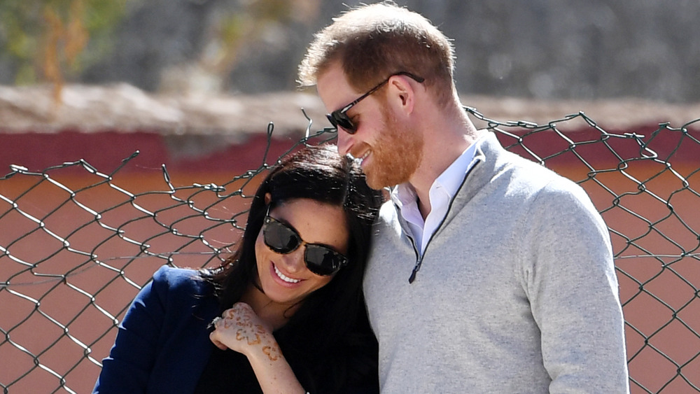 Meghan Markle et le prince Harry sourient bras dessus bras dessous