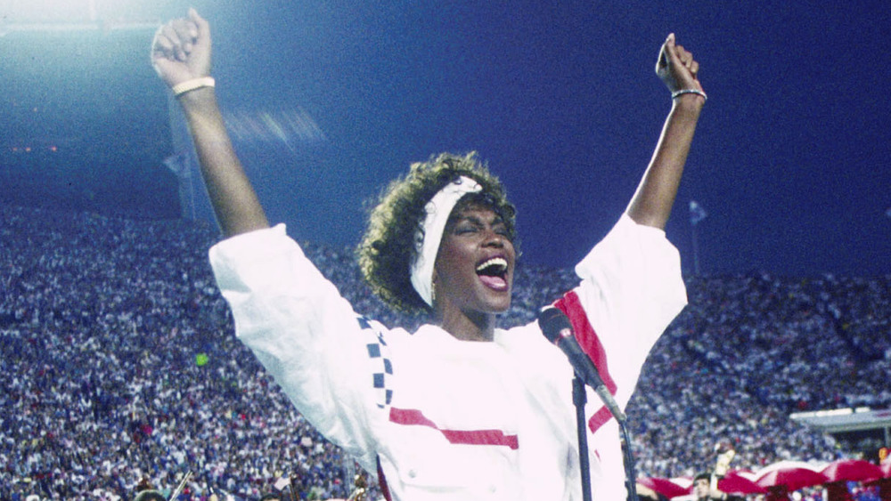 Whitney Houston avec les mains en l'air, chantant