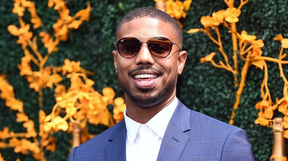 Michael B.Jordan devant un mur herbeux et fleuri