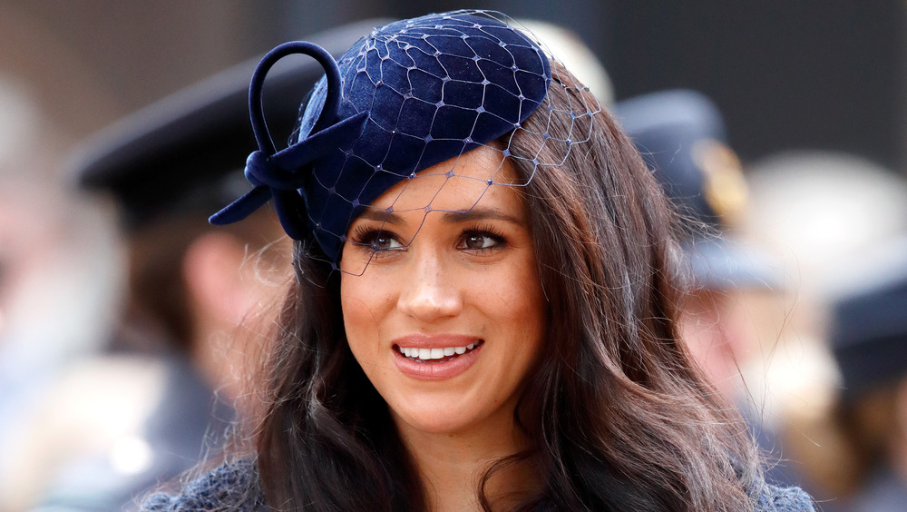 Meghan Markle, la duchesse de Sussex, souriante et vêtue de bleu marine