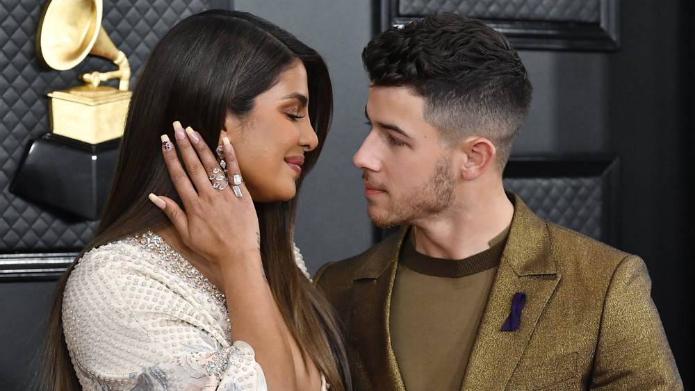 Priyanka Chopra sourit à Nick Jonas pendant qu'il la regarde dans les yeux