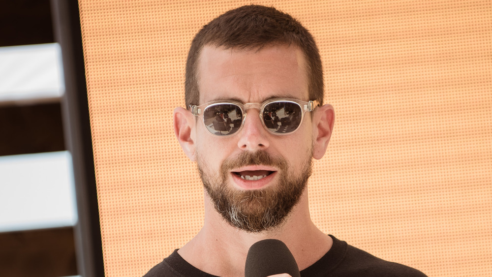 Jack Dorsey parlant dans un microphone avec des lunettes de soleil sur