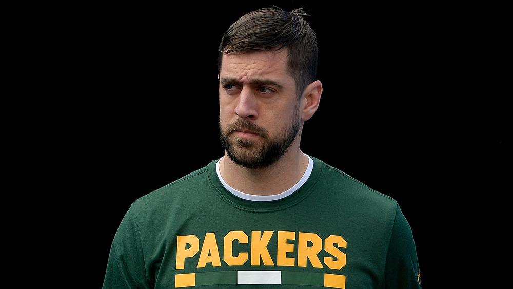 Aaron Rodgers dans un t-shirt des Green Bay Packers avec un fond sombre 