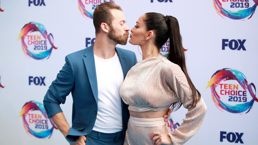 Artem Chigvintsev et Nikki Bella s'embrassent sur un tapis rouge