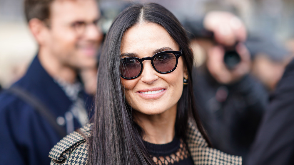 Demi Moore porte des lunettes de soleil marron et sourit à la caméra lors d'un événement