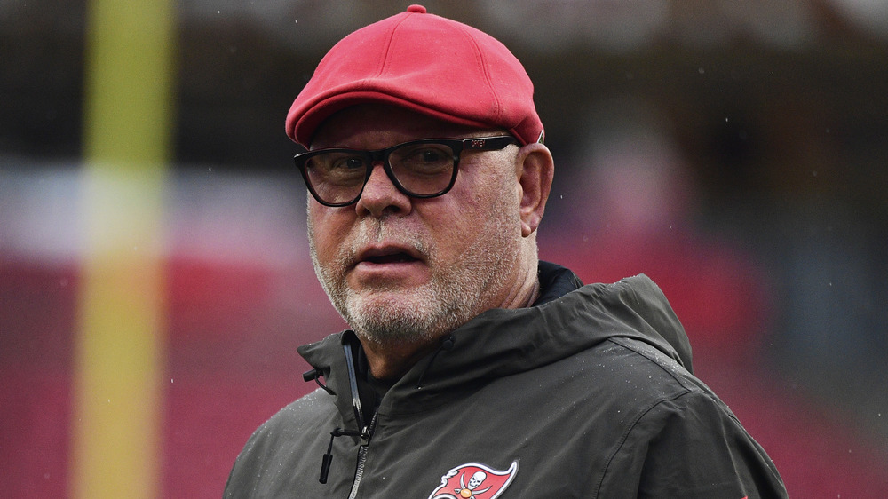 Bruce Arians dans des lunettes à monture noire se penche sur la caméra