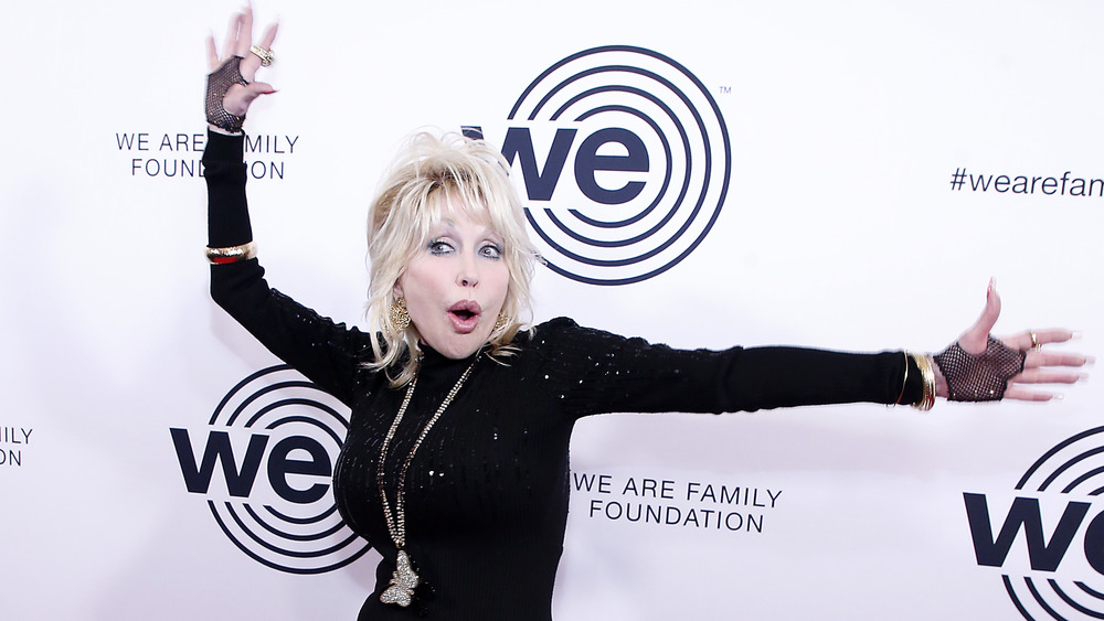 Dolly Parton avec les mains en l'air sur le tapis rouge