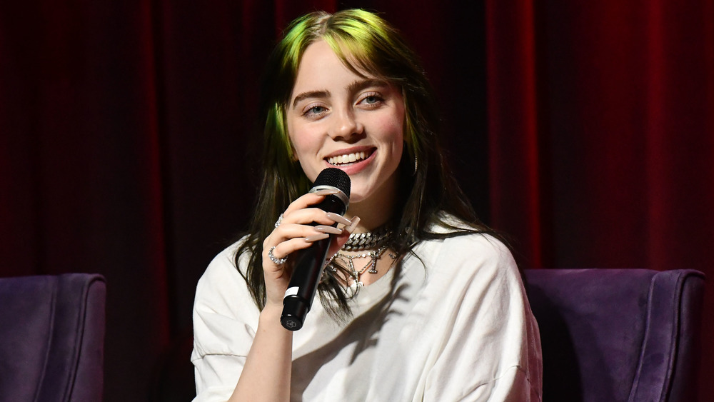 Billie Eilish souriant et tenant un microphone 