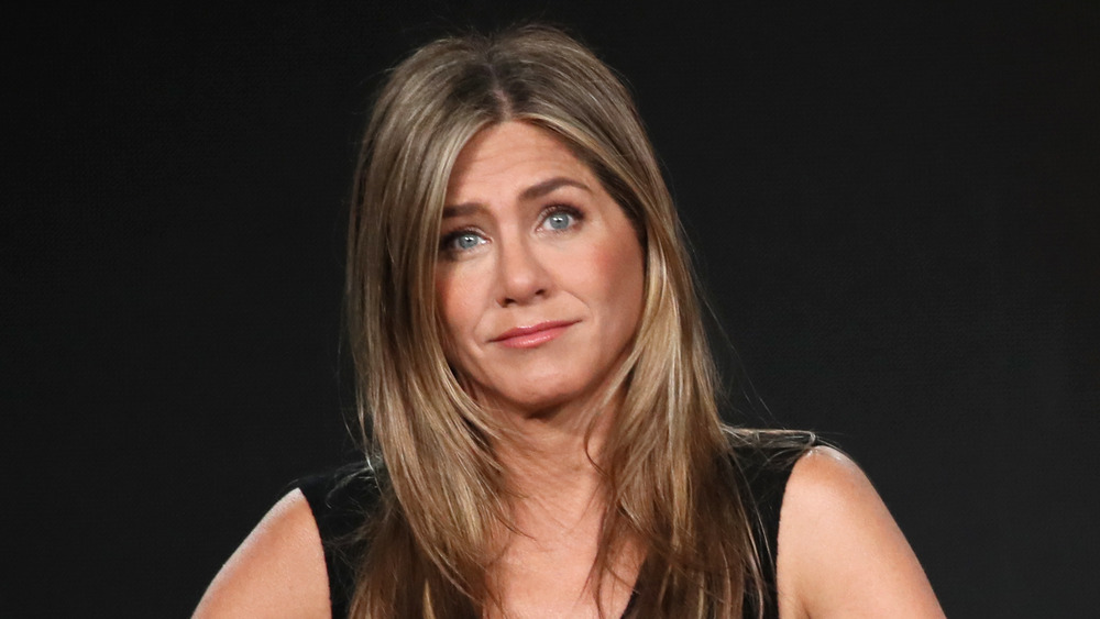 Jennifer Aniston dans une robe noire, haussant les épaules