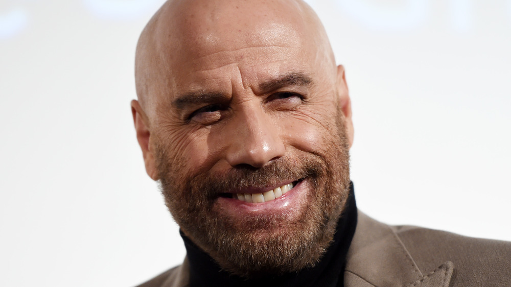 John Travolta sourit lors d'un événement sur le tapis rouge