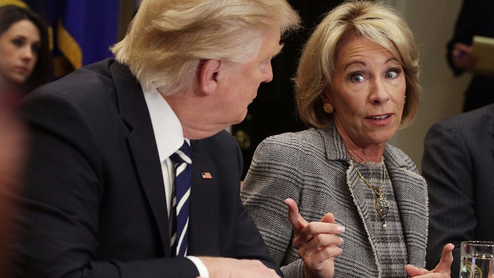 Le président Trump regarde Betsy DeVos du doigt