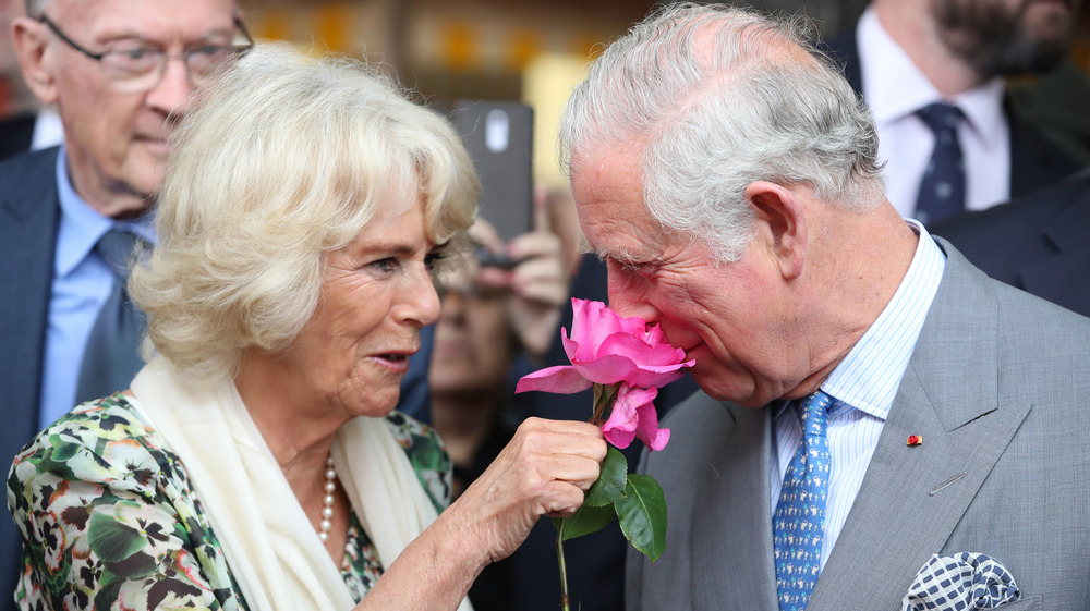 Camilla duchesse de Cornouailles tenant une fleur pour que le prince Charles sente