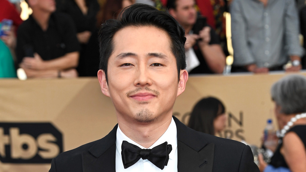 Steven Yeun souriant dans un smoking 