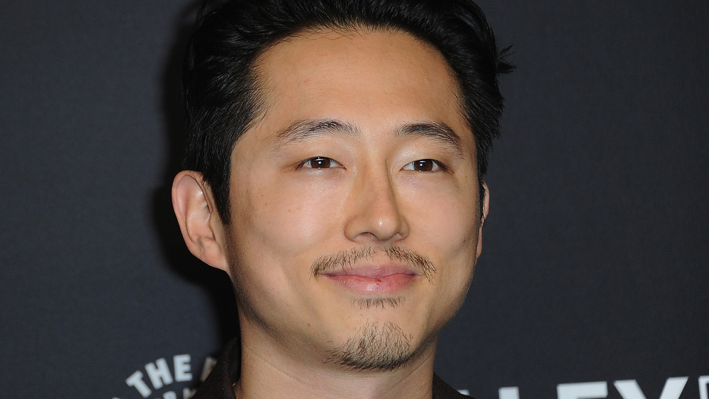 Steven Yeun avec un sourire narquois