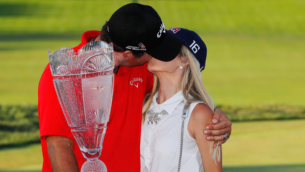 Patrick Reed et Justine Reed s'embrassant, tous deux coiffés de chapeaux, sur le terrain de golf, coiffés de chapeaux