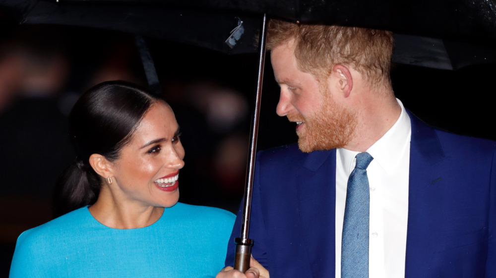 Meghan Markle et le prince Harry rient sous un parapluie